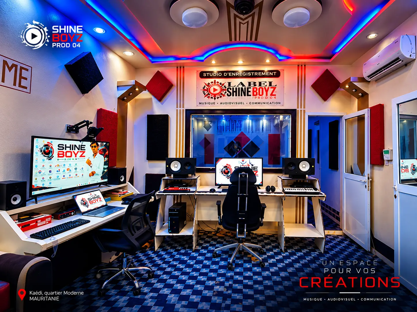 Poste de production du studio avec deux écrans, panneaux acoustiques rouges et moquette bleue